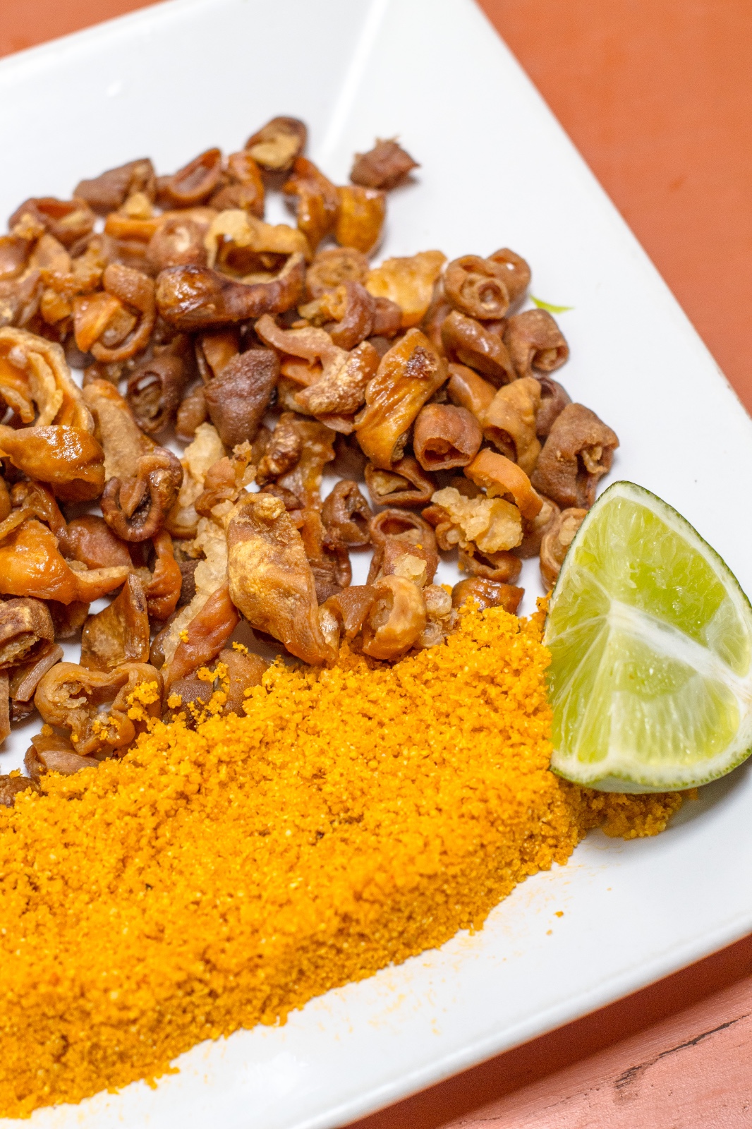 Porção dourada e crocante servida com farofa e limão